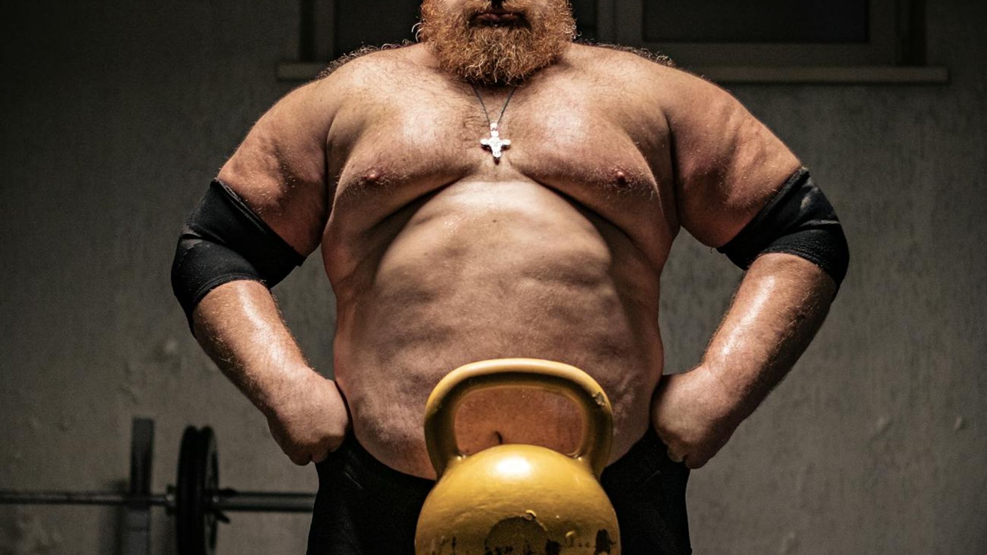 Strong man performing exercises in a dark gym environment